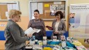 Na zdjęciu widać dwie pracownice Wojewódzkiego Urzędu Pracy w Warszawie Filia w Ciechanowie, które udzielają informacji osobie zainteresowanej, która odwiedziła stoisko wystawiennicze.